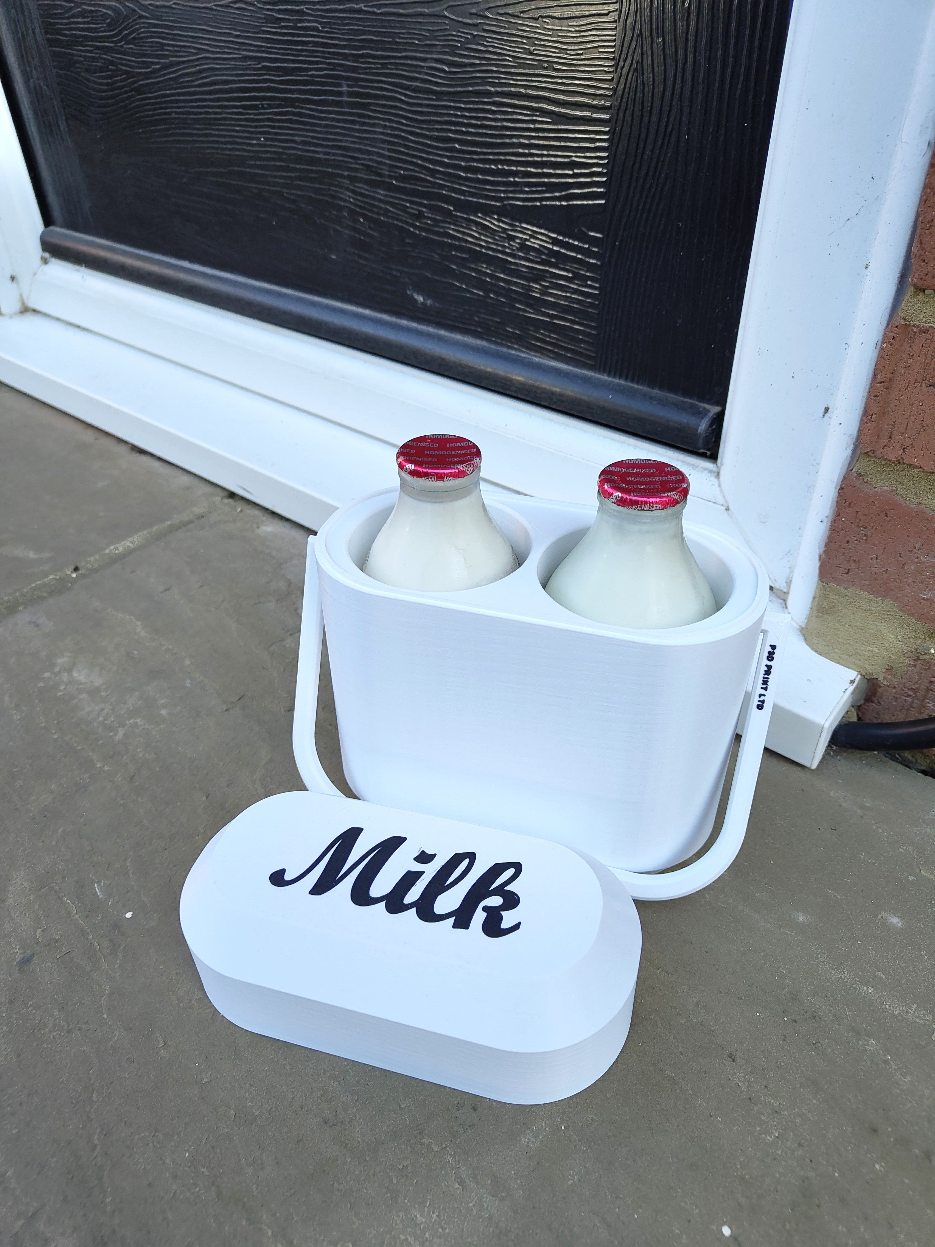 White milk crate with two bottles of milk and a lid labeled 'Milk' on a concrete surface.